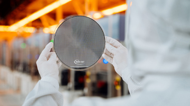 Ein Techniker im Reinraum von Infineon Technologies in Villach, Österreich, hält einen 200 mm Siliziumkarbid-Wafer. / A technical engineer in the cleanroom at Infineon Technologies in Villach, Austria, holds a 200 mm silicon carbide wafer.